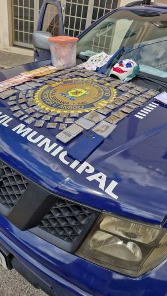 Veículo da Polícia Civil Municipal com materiais apreendidos em cima do capô, incluindo drogas, uma máscara e outros objetos.