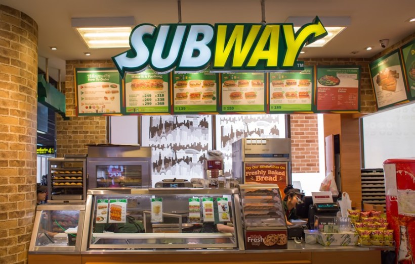 Interior of a Subway sandwich shop featuring the logo, menu boards, and food counters.