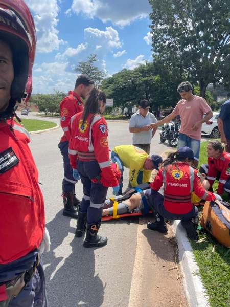 Equipe de resgate prestando atendimento a uma vítima em um acidente, com vários profissionais de emergência e curiosos ao redor.