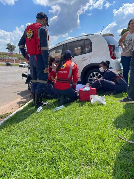 Equipe de socorristas prestando atendimento em acidente de trânsito com um carro branco.