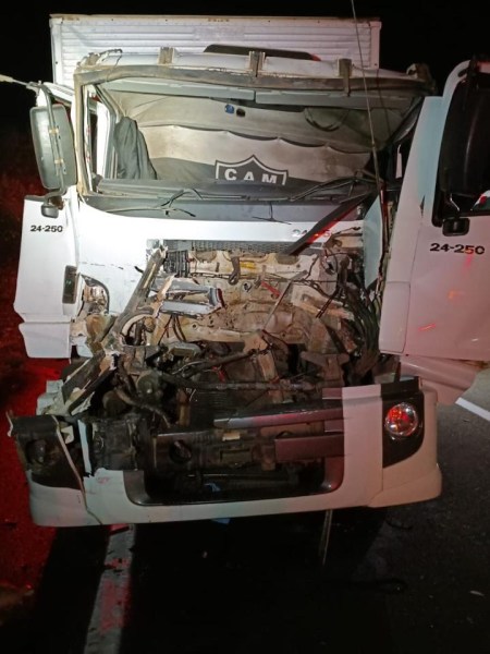 Caminhão com a frente danificada, mostrando motor exposto após um acidente.