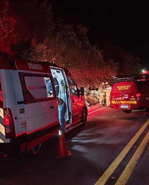 Veículo de emergência próximo a um deslizamento de terra à noite, com bombeiros atendendo a situação.