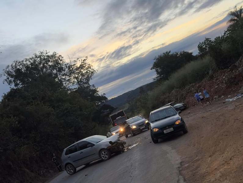 Acidente de carro em uma estrada, com vários veículos parados e um céu nublado ao fundo.