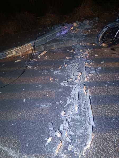 Ruído de asfalto danificado com pedras soltas e fissuras visíveis, à noite.