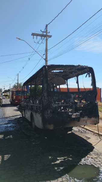 Ônibus parcialmente queimado em uma rua, com estrutura danificada e detalhes de fumaça ainda visíveis.