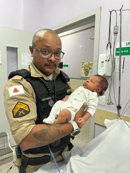 Policial segurando um bebê recém-nascido em um hospital.