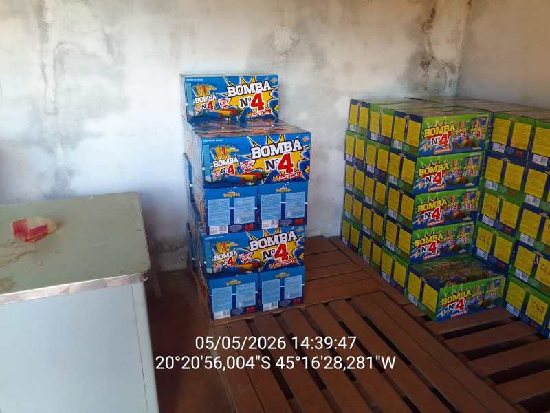 Caixas de fogos de artifício, marca 'Bomba N° 4', empilhadas em um ambiente interno com um tampo de mesa de metal ao fundo.