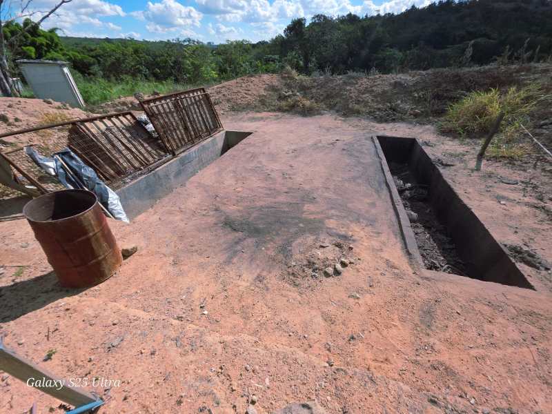 Área de construção com duas fossas cavadas no solo, cercadas por um terreno árido e unidas por um caminho de terra.