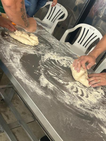 Duas pessoas amassando massa de pão em uma superfície enfarinhada.