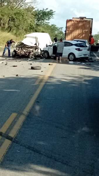Cenário de um acidente de carro em uma estrada, com dois veículos danificados e pessoas ao redor.