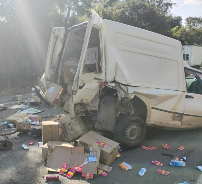 Furgão acidentado na estrada com caixas e produtos espalhados pelo chão.