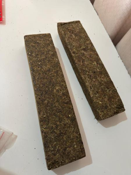 Dois blocos retangulares marrons, que parecem ser feitos de material vegetal, sobre uma superfície branca.