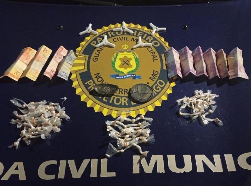 Drogas e dinheiro apreendidos sobre uma mesa com o emblema da Guarda Civil Municipal.