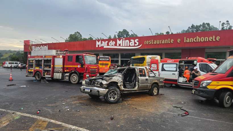 Acidente automobilístico com um veículo danificado e veículos de emergência em um posto de gasolina e restaurante.