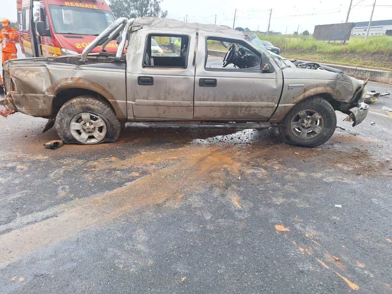 Caminhonete cinza danificada em um acidente, com rodas danificadas e óleo derramado na estrada.