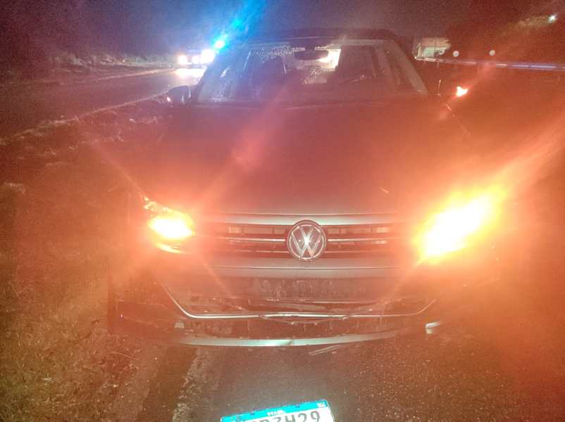 Carro da Volkswagen com faróis acesos à beira da estrada durante a noite.