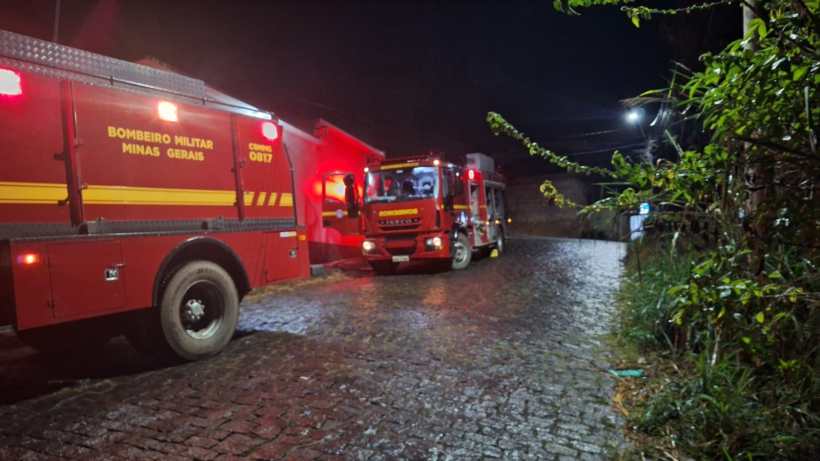 Veículo dos Bombeiros Militares de Minas Gerais parado em uma rua de paralelepípedo à noite, com luzes vermelhas ativadas.