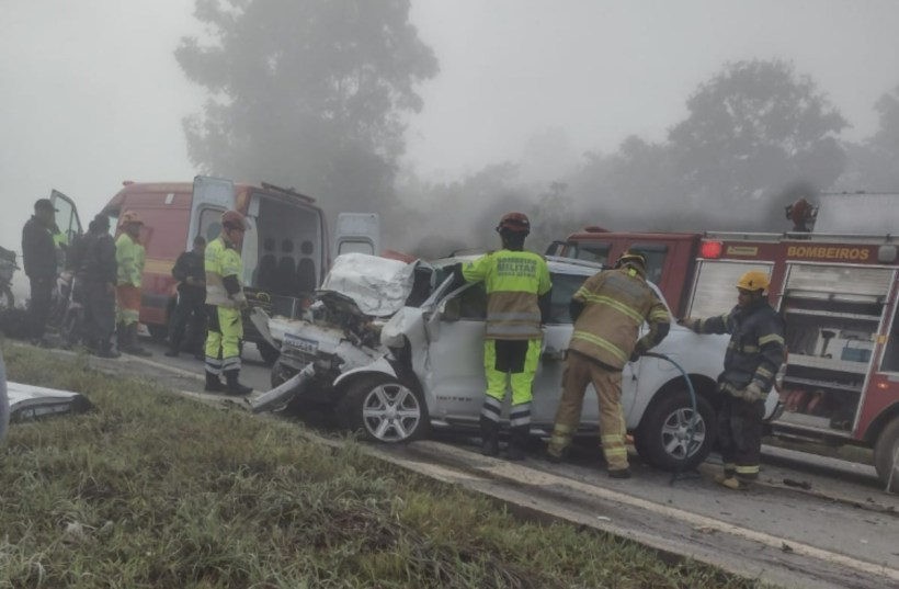 Acidente de carro com veículo danificado e equipes de resgate trabalhando na cena.