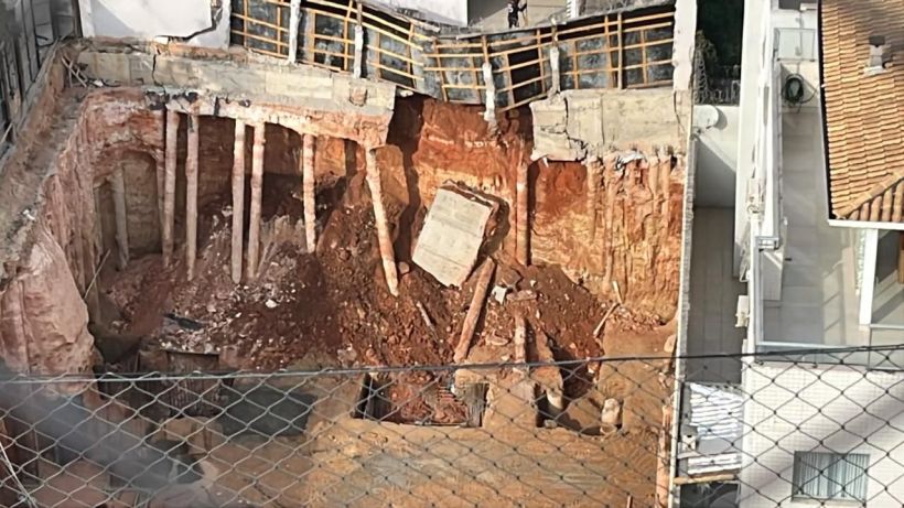 Imagem de uma escavação profunda em um canteiro de obras, com pilastras expostas e terra acumulada ao redor.