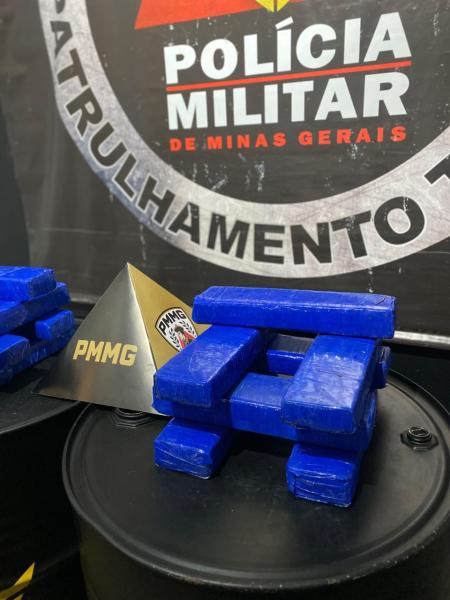 Representação de tabletes de drogas em formato de blocos azuis, com um prisma dourado identificado como PMMG ao lado, em um fundo com logo da Polícia Militar de Minas Gerais.