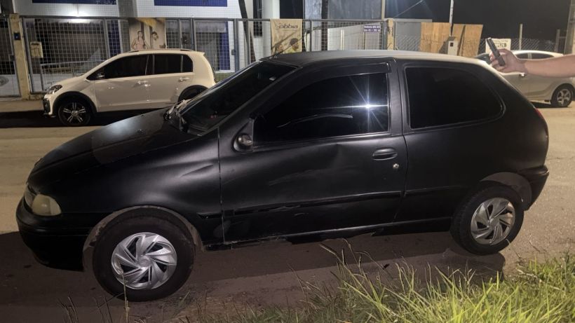 Carro preto estacionado na rua à noite, com janelas escuras e rodas prateadas.