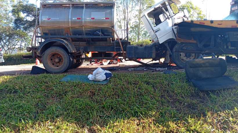 Um caminhão tanque parado ao lado da estrada, com um compartimento vazio e ferramentas espalhadas ao redor.