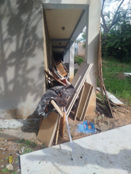 Acúmulo de entulho e materiais de construção em um corredor estreito ao ar livre.