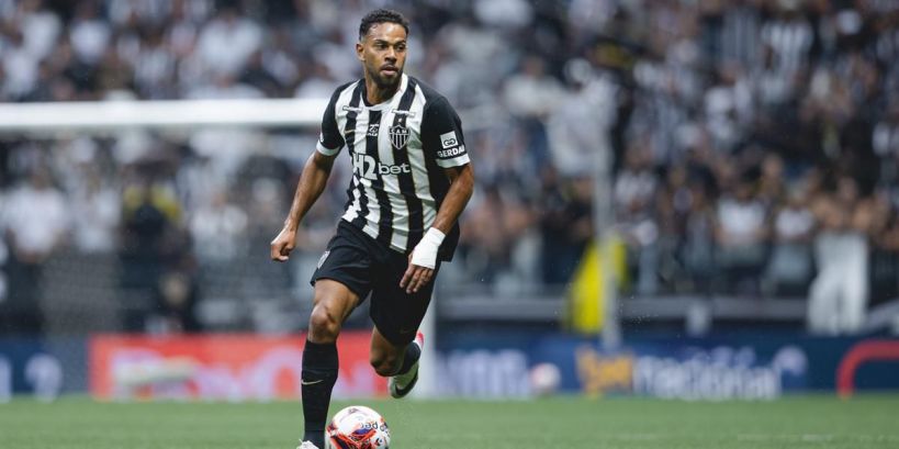 A football player in a black and white striped jersey dribbling a ball during a match.