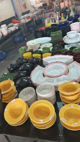 Variadas tigelas e pratos dispostos em uma mesa de feira, com diferentes cores e estilos.