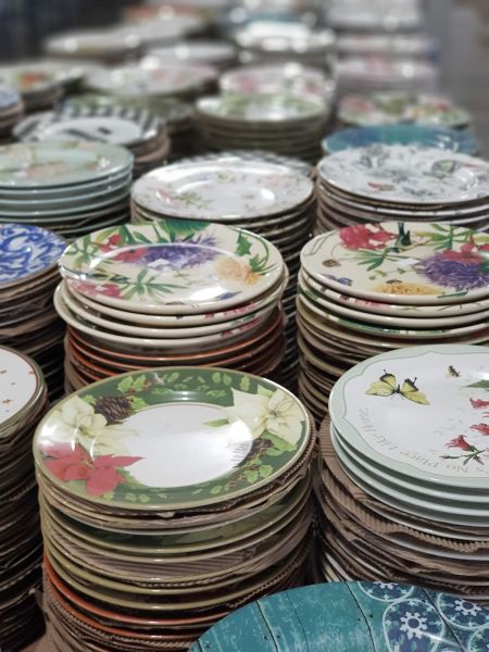 Pilhas de pratos decorativos empilhados, alguns com flores e borboletas, exibindo uma variedade de designs.
