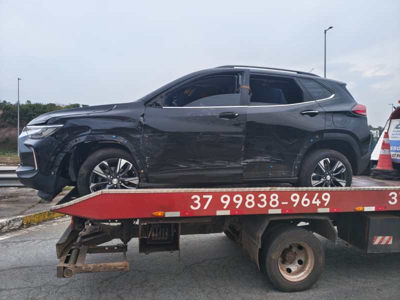 Carro preto danificado sendo transportado em um guincho.