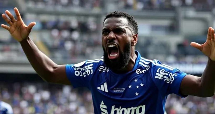 A football player in a blue jersey celebrating passionately with outstretched arms and an intense expression during a match.