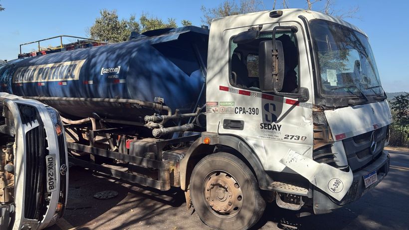 Caminhão tanque azul de abastecimento de gás estacionado na estrada, com um veículo branco tombado ao lado.