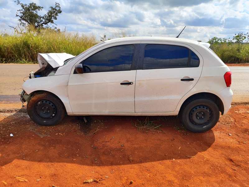 Um carro branco estacionado em uma estrada, com o capô aberto, revelando o motor.