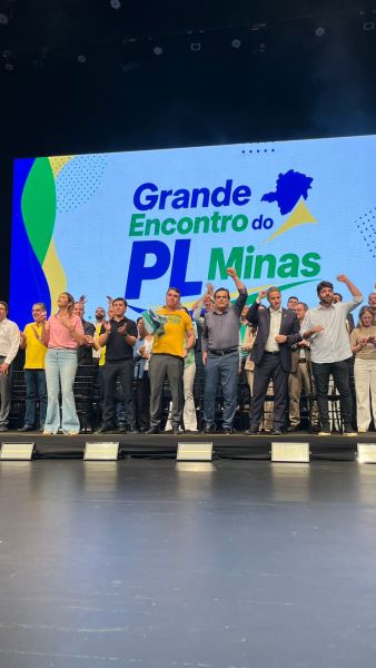 Pessoas em um palco durante o Grande Encontro do PL Minas, com um fundo colorido destacando o nome do evento.