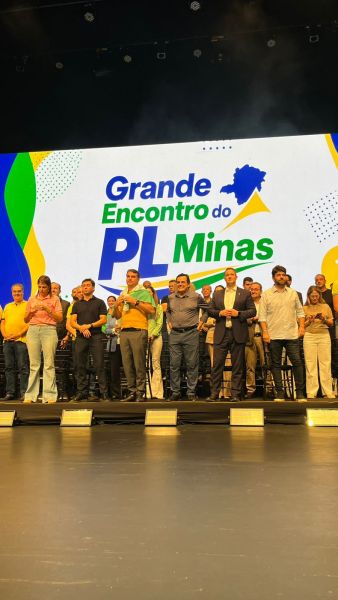 Evento político chamado "Grande Encontro do PL Minas" com um grupo de pessoas em um palco, ao fundo um banner colorido com o nome do evento.