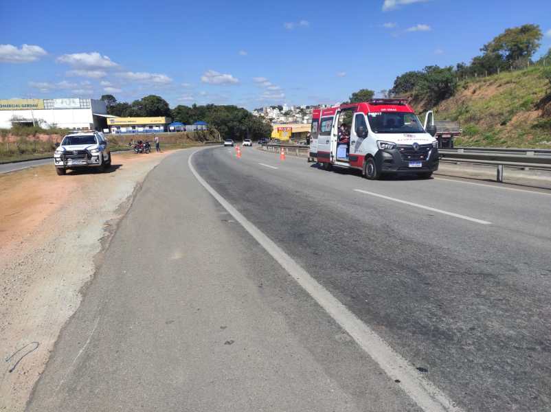 Ambulância estacionada na estrada, com cones de sinalização, ao lado de um veículo particular. Cenário de rodovia sob céu claro.