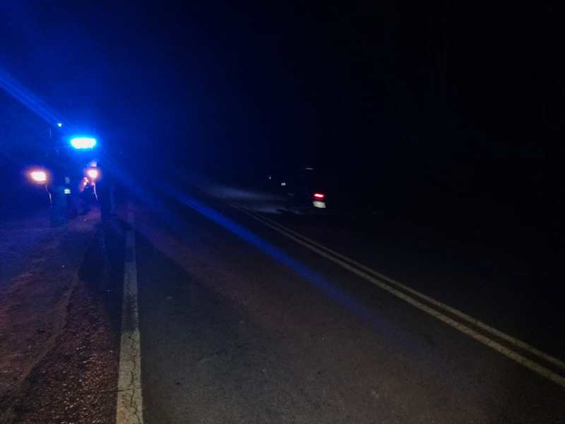 Estrada à noite com luzes azuis de um veículo policial.