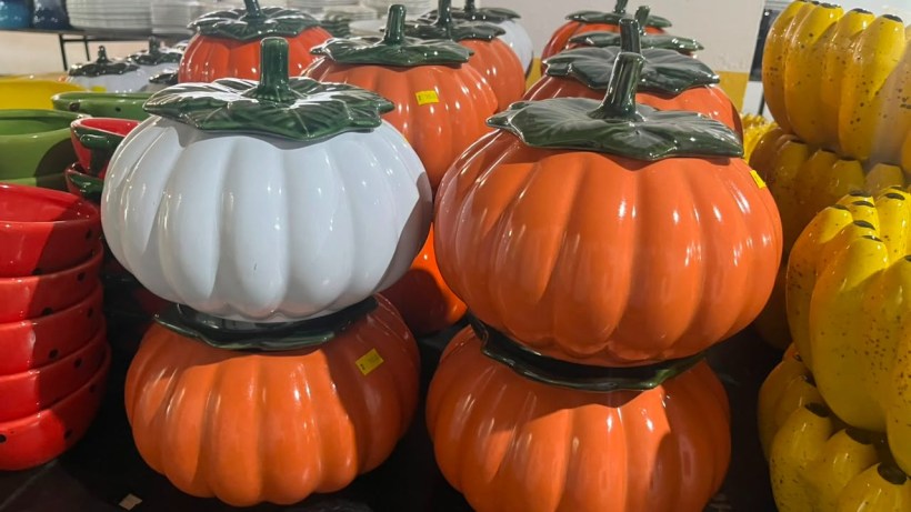 Stack of colorful ceramic pumpkin-shaped containers in orange, white, and yellow hues.