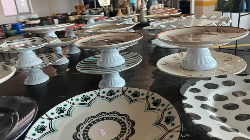Collection of decorative plates and cake stands displayed on a wooden table, featuring various designs and colors.