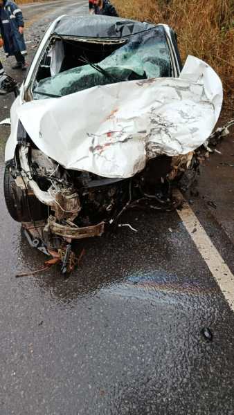 Carro com frente destruída após acidente, com danos significativos visíveis na estrutura e no capô.