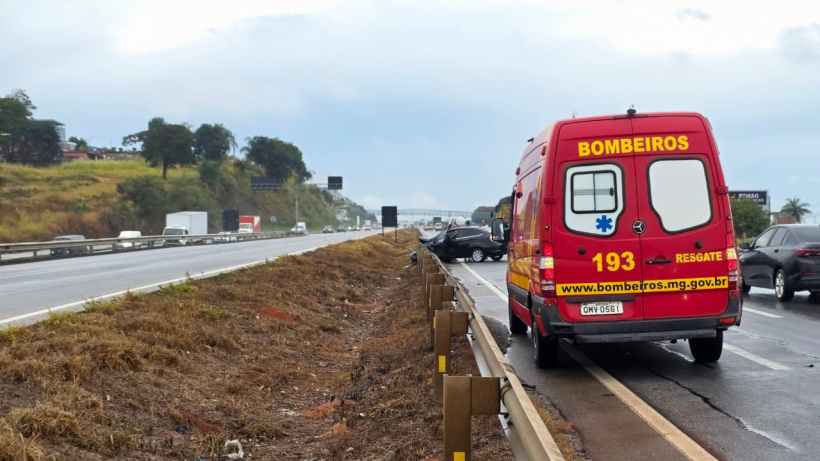 Veículo de emergência dos bombeiros estacionado à beira da estrada, com um acidente de carro visível ao fundo.