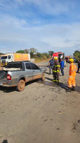 Equipe de resgate examina um carro acidentado na estrada, com bombeiros e profissionais de emergência presentes.