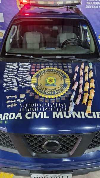 Veículo da Guarda Civil Municipal com um layout exibindo drogas apreendidas em sua capô, incluindo várias embalagens organizadas em fileiras.