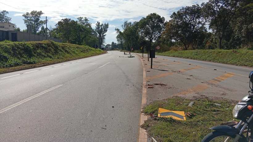 Imagem de uma estrada vazia com vegetação ao lado, onde podem ser vistos detritos e um sinal de trânsito.