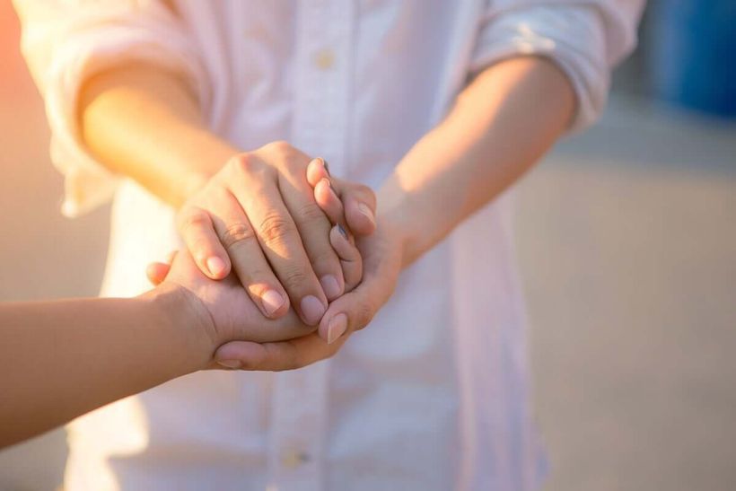 Two hands clasping together in a gesture of connection and support.