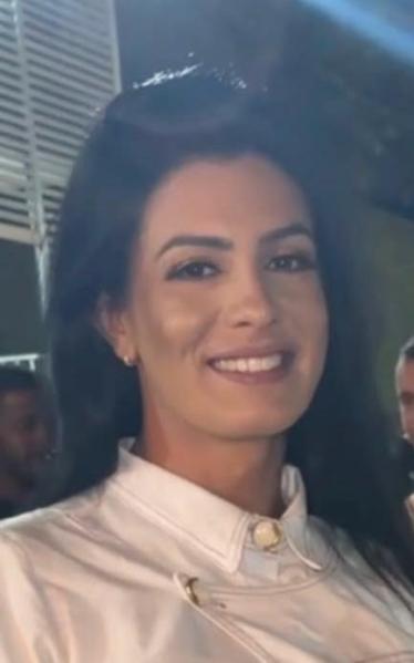 Retrato de uma mulher sorridente, com cabelo preto e liso, vestindo uma blusa branca.