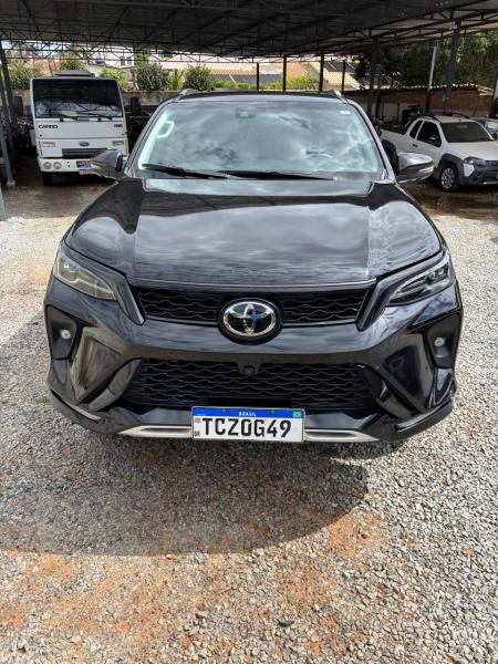 Frente de um SUV preto da Toyota estacionado em um terreno de cascalho.
