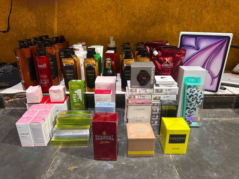 Vários frascos de produtos de beleza e fragrâncias dispostos sobre uma superfície, incluindo shampoos, condicionadores e perfumes de diferentes marcas.