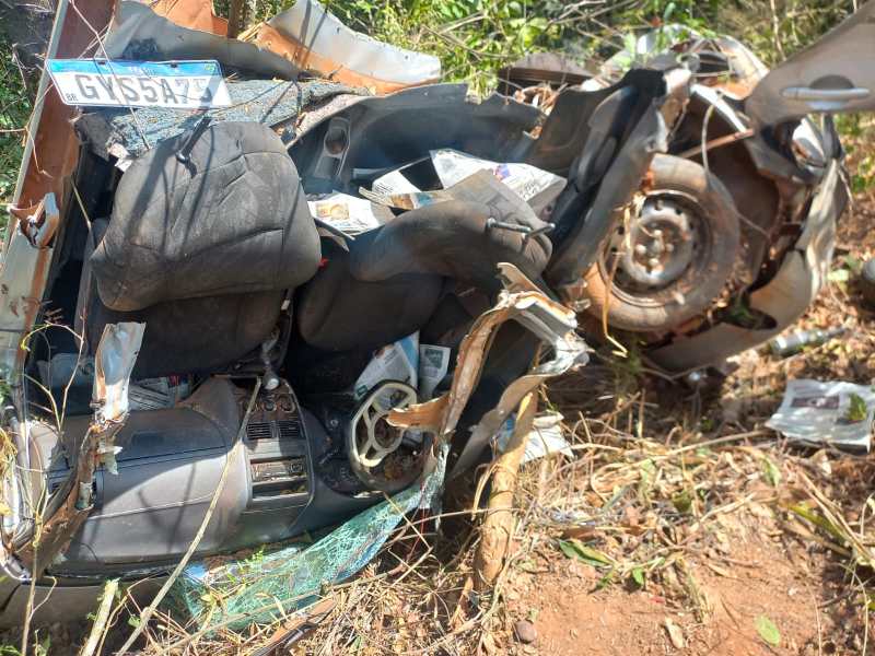 Interior de um carro acidentado, com bancos danificados e detritos ao redor.